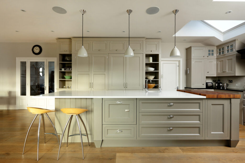Kitchen display with MDF finish - grey kitchen cabinets with wood flooring, yellow seats and cream background. 