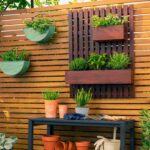 Sadolin Quick Dry Woodstain Lifestyle - brown stained wood in a garden setting with potted plants.